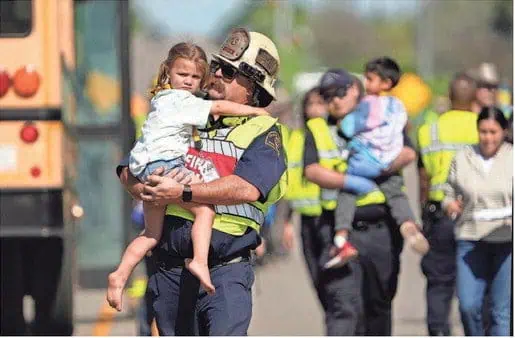 An officer carrying a little girl after a school bus accident