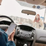 Car driver distracted by phone while driving, approaching a female pedestrian, highlighting the dangers of distracted driving.