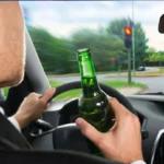Abogado de Austin especializado en accidentes por saltarse un semáforo en rojo: Un conductor con una botella de licor en la mano mientras se saltaba un semáforo en rojo pone de relieve los peligros de conducir ebrio y las infracciones de tráfico.