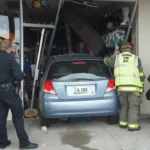 Car involved in a storefront crash with rescuers aiding and investigating the scene, relevant for personal injury claims.