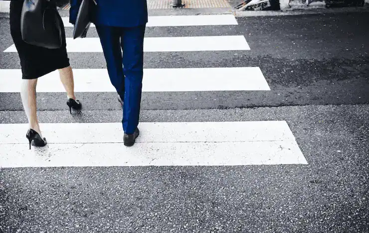 A man and woman walking in a crosswalk pointing out the thought: who Is liable in a pedestrian accident